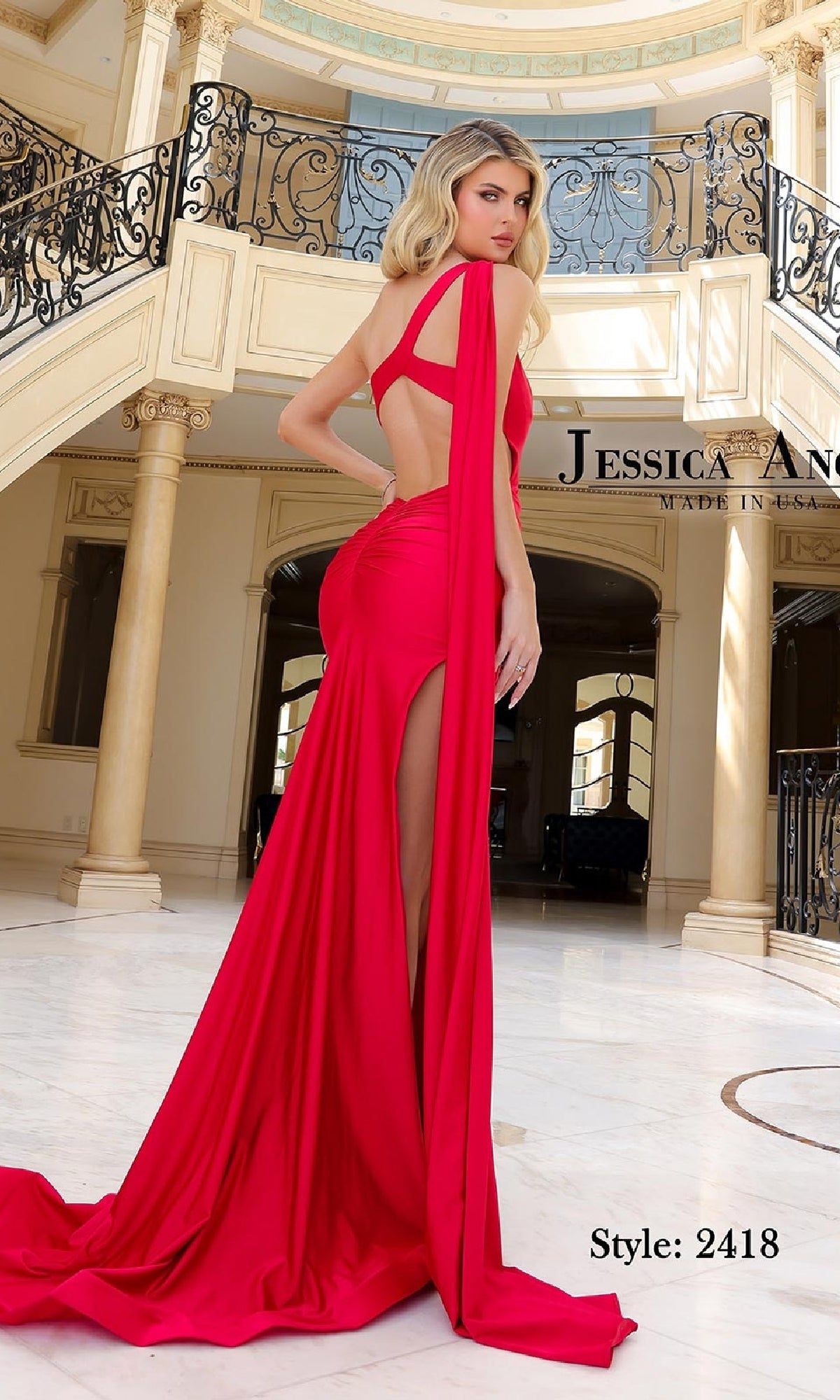 A woman in the Jessica Angel 2418 Shoulder-Drape Long Prom Dress stands gracefully in an elegant, marble-floored room with ornate railings and columns.